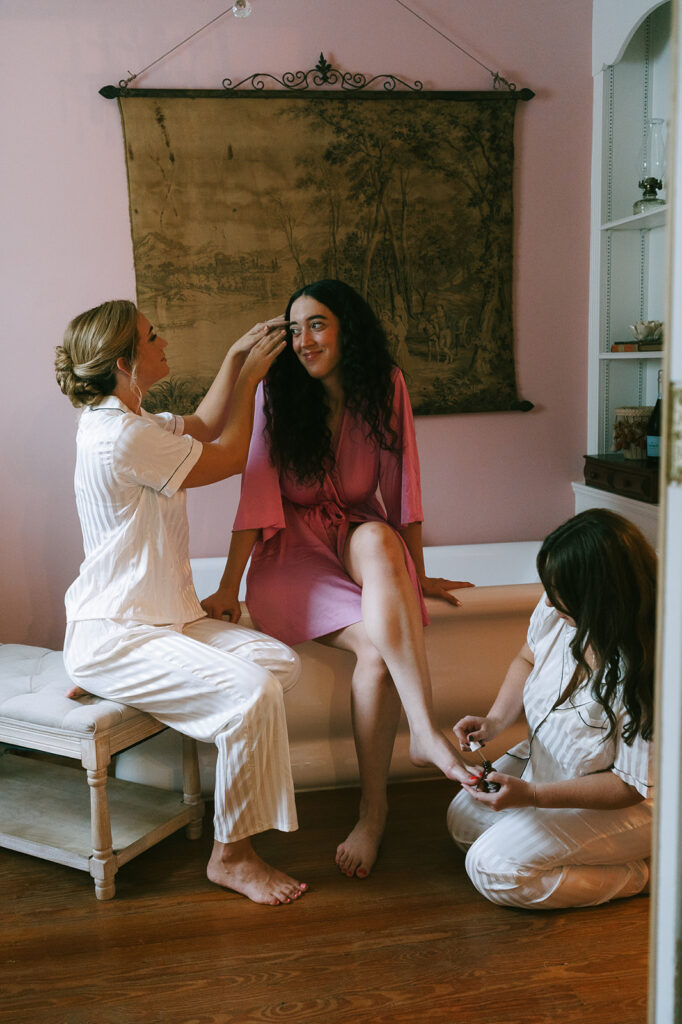 cute picture of the bridesmaids helping the bride get ready for her coquette themed wedding