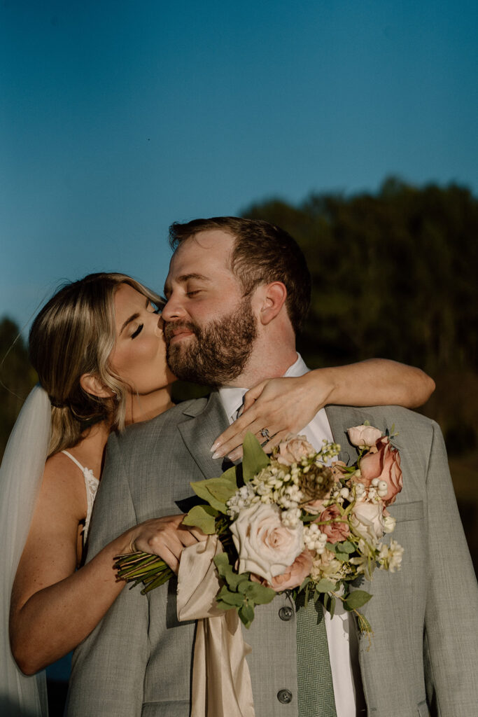 portrait of the bride kissing the groom on the cheek
