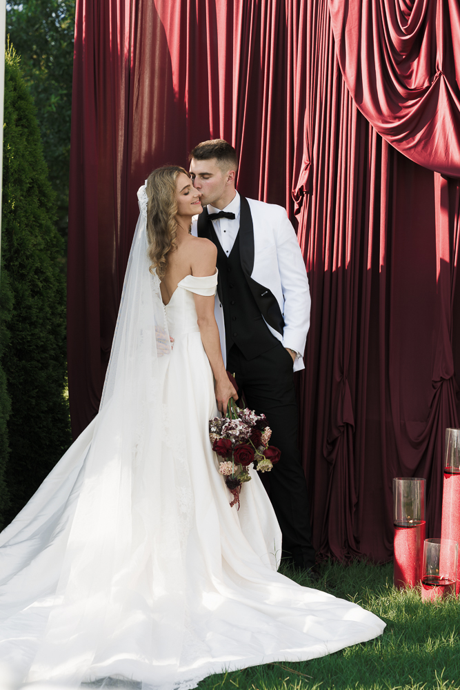 Groom, kissing the bride on the cheek