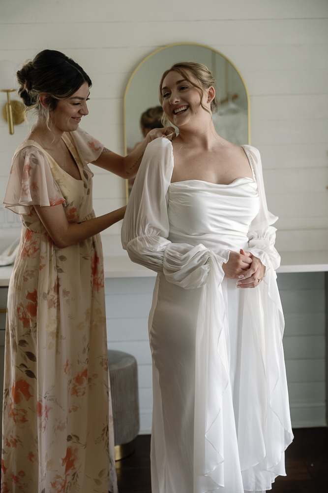 Bridesmaid helping the bride with her wedding dress