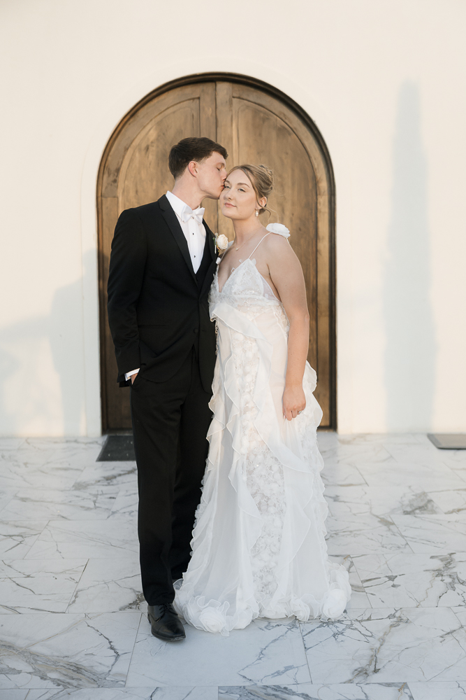 Groom, kissing the bride on the cheek