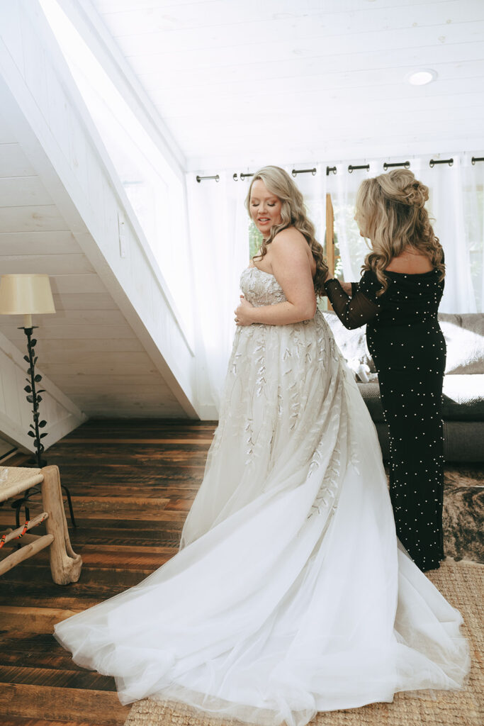 mother of the bride helping her with her wedding dress