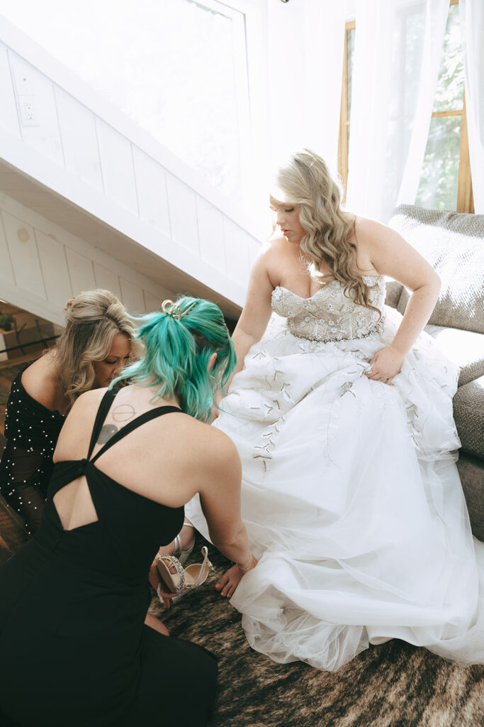 bridesmaids helping the bride with her wedding shoes