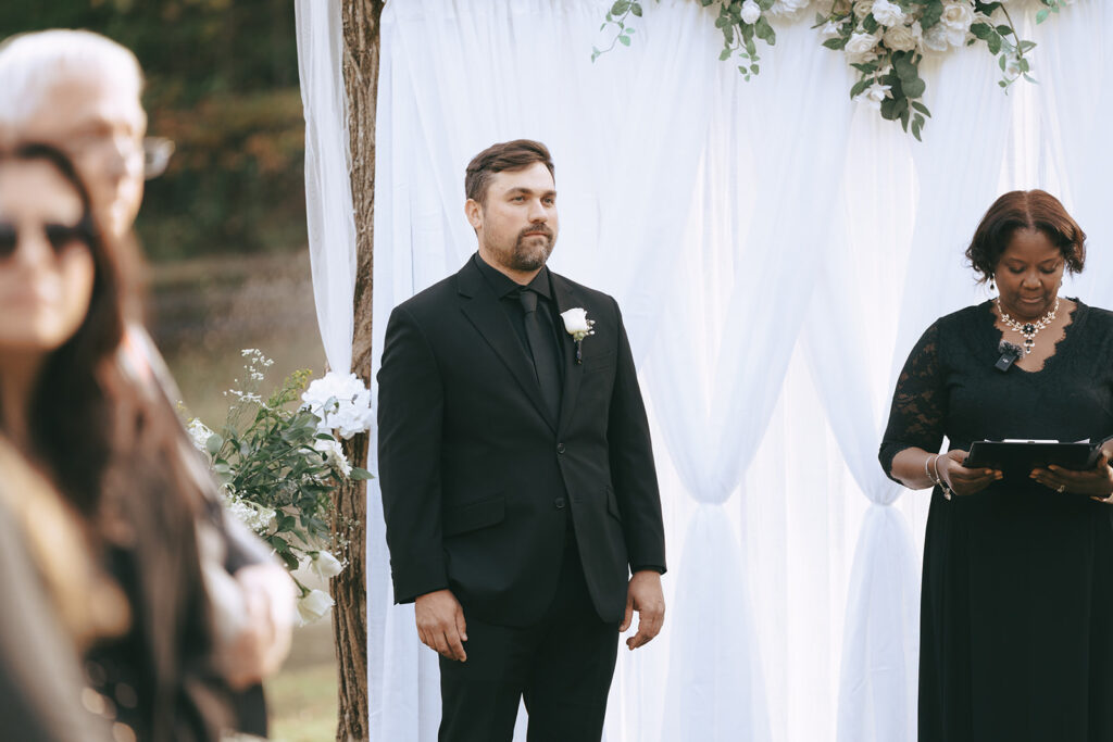 groom watching the bride  walk down the aisle