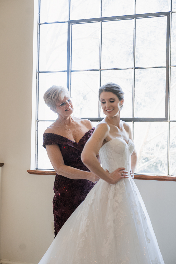 Mother of the bride helping her with the wedding dress