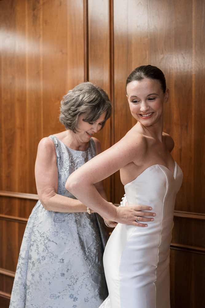 mother of the bride helping her with the wedding dress